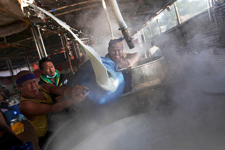 FTA: Altaf Qadri: Buddhist volunteers react as they pour milk into a huge pot to prepare tea 