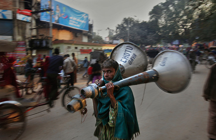 FTA: Altaf Qadri: An Indian worker carries a pair of loudspeakers 