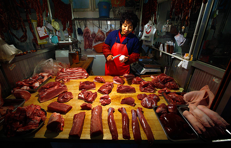 24 hours in pictures: A woman cuts a pig's trotter for a customer at her small pork stall, China