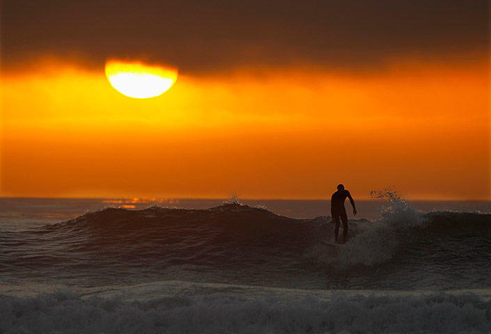 24 Hours: A surfer rides his last wave into shore as the sun sets in California