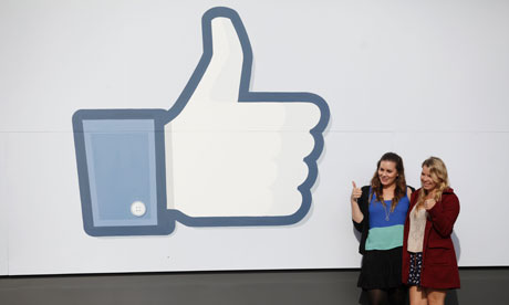 Girls pose in front of Facebook sign