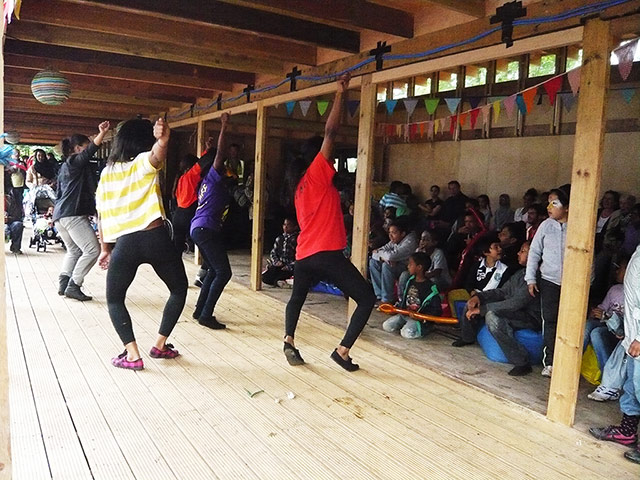 Oasis Childrens' Venture: Children dance on a timber Veranda as family and friends watch