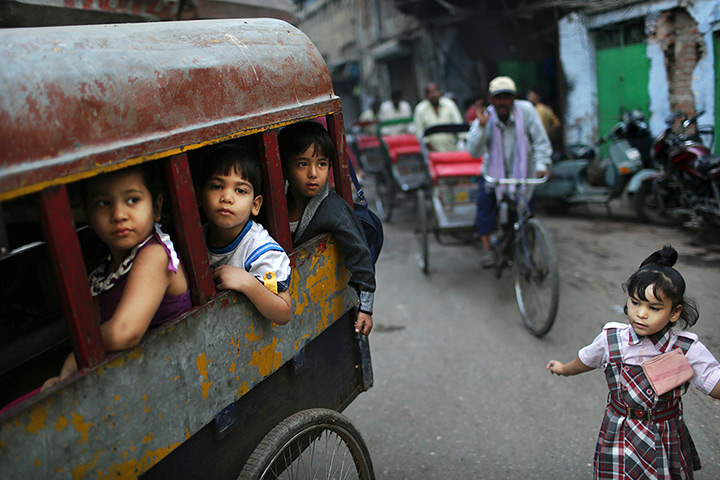 24 horus in pictures: Indian school children wait in the back of a bicycle rickshaw