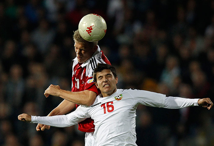 wcq 2: Bulgaria's Milanov jumps for the ball with Denmark's Cornelius