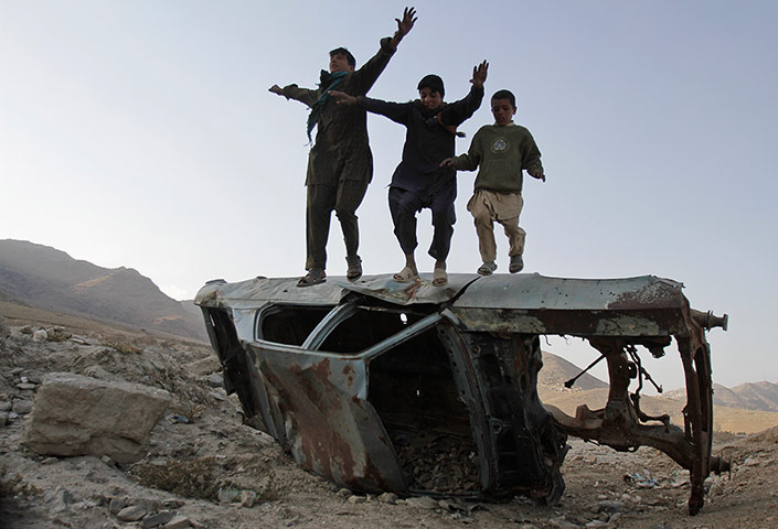 24 hours: Children jump from a destroyed car left on the side of a road in Kabul