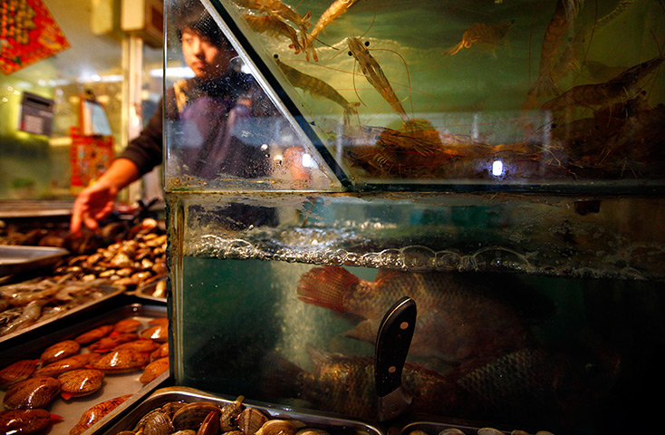 24 hours: Beijing, China: A seafood vendor serves a customer at a small food market 