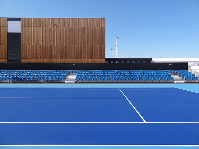 Stanton Williams projects: A large blue outdoor sports' court with spectator seating