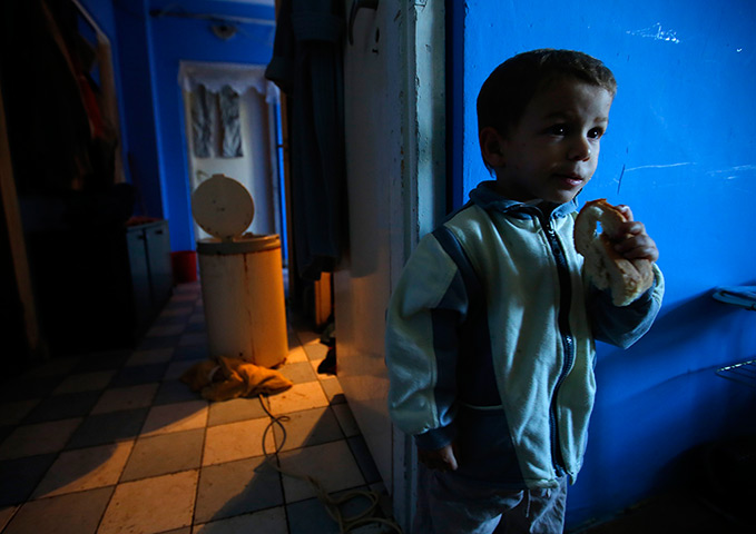24 hours: Miskolc, Hungary: A Roma boy eats a slice of bread in his apartment