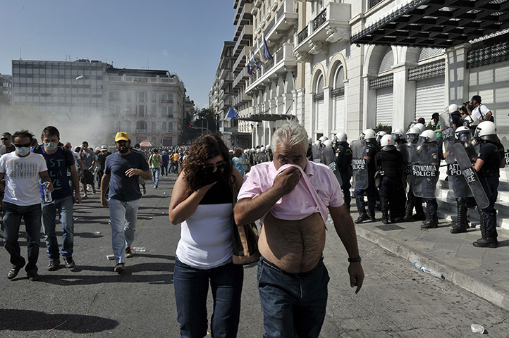 Greece protests: Protesters cover their faces and march amid tear gas