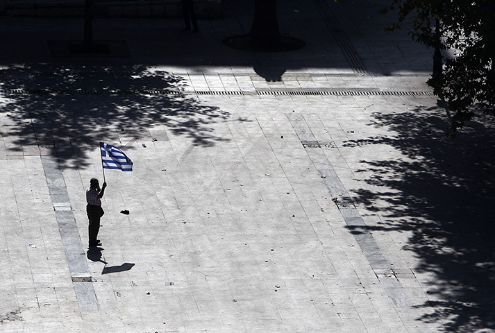 Greece protests: A elderly protester holds a Greek flag in a deserted Syntagma square