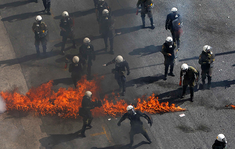 Greece protests: Greek riot police try to avoid flames from a molotov cocktail