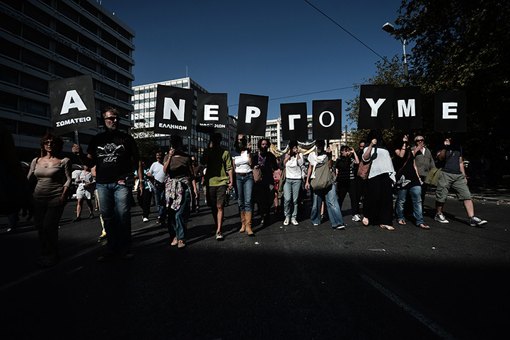 Greece protest update: Demonstrators hold banners reading 'we work as unemployees' during a rally