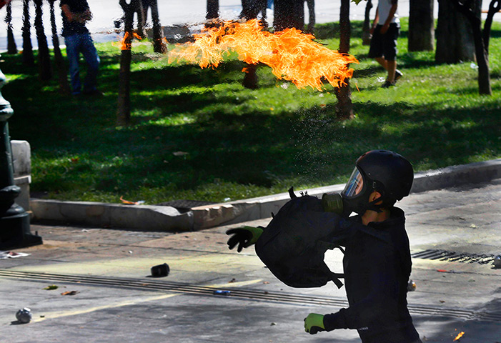Greece protest update: A protester throws a petrol bomb at riot police during a violent clashes