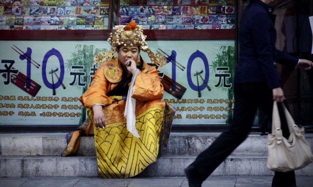 A troubled looking store greeter dressed as a Chinese historical figure to attract customers sits outside a shop in Beijing. Figures released today have shown a slowdown in the growth of the Chinese economy