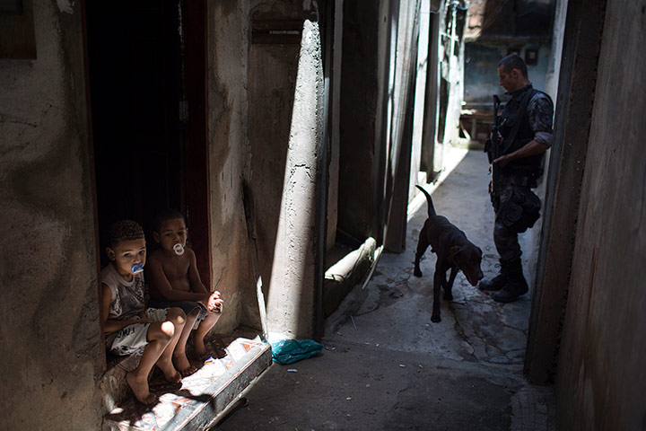 20 Photos: Boys sit outside their home as a police officer patrols in Rio