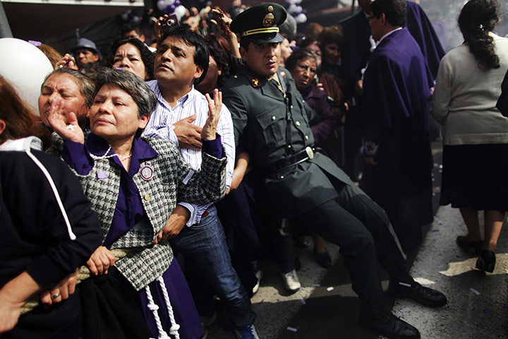 20 Photos: A police officer restrains the crowd at 'The Lord of Miracles' in Lim