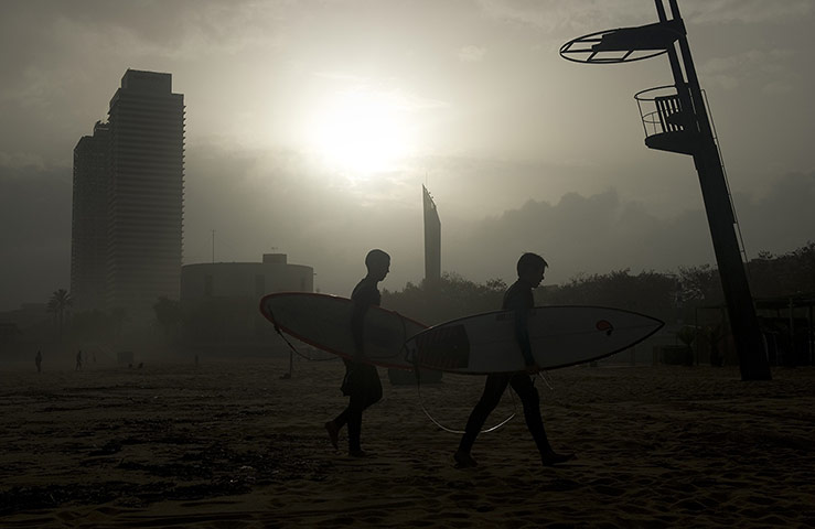 24 Hours: Surfers walk on a beach in Barcelona
