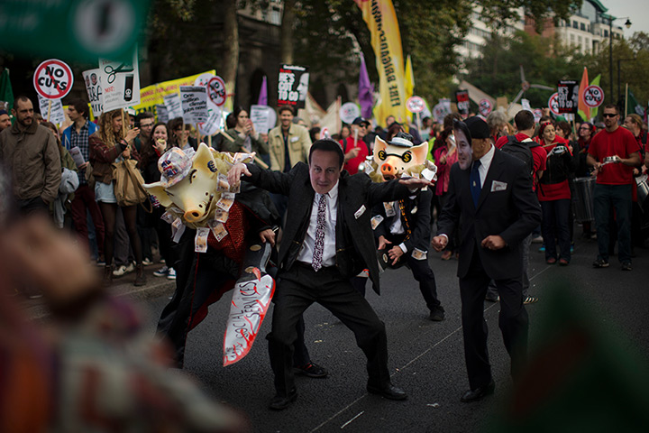 24 hours in pictures: demonstrator wearing a mask depicting David Cameron takes part in protest