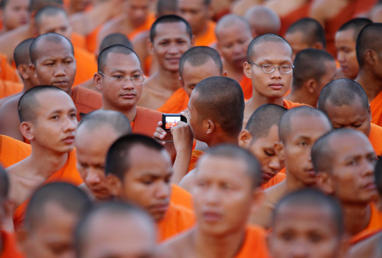 A Cambodian Buddhist monk takes pictures during a ceremony in front of the Royal Palace, Phnom Penh