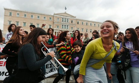 A student plays the trumpet as others dance around her during an anti-austerity protest, in front of the parliament in Athens October 23, 2012.