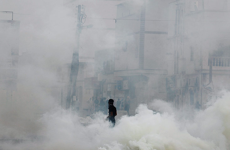 20 Photographs: An anti-government protester during clashes with riot police in Mameer