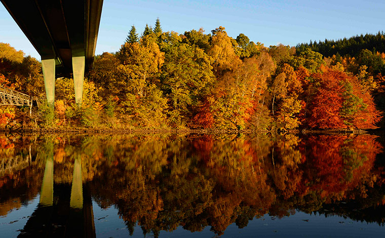 24 hours: Autumn trees are reflected in the water of Faskally Loch, Scotland