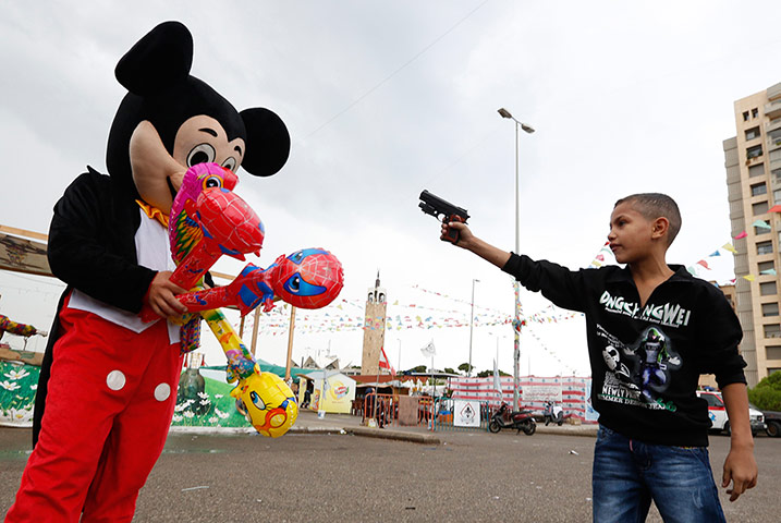 24 hours: A Syrian refugee boy points a plastic toy pistol at Mickey Mouse