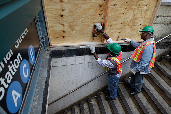 Hurricane Sandy : Workers cover a station entrance with plywood to help prevent flooding