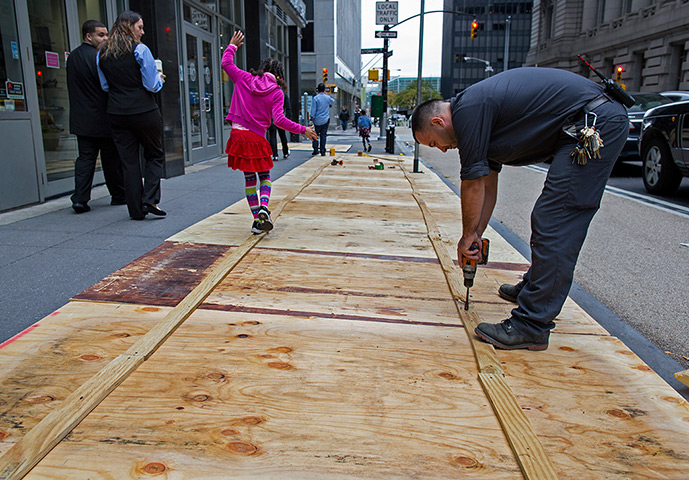 Hurricane Sandy : A maintenance worker attaches plywood to a sidewalk grate