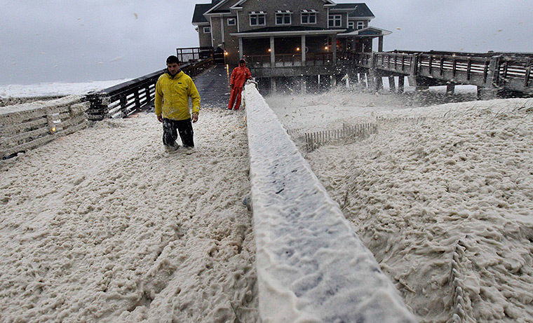 Hurricane Sandy : A news crew wades through sea foam blown onto Jeanette's Pier 