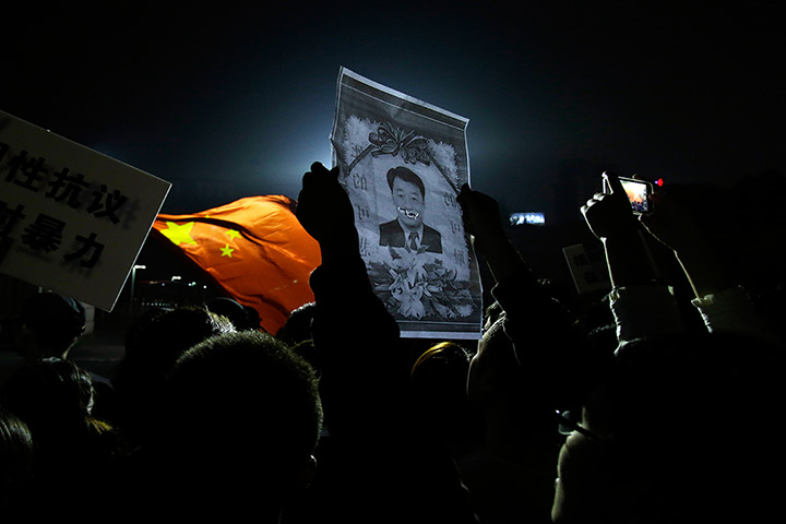 24 hours: Ningbo city, China: Protesters hold up a defaced picture of the city mayor