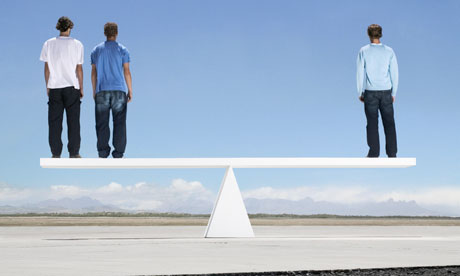 Three men standing on see saw outdoors