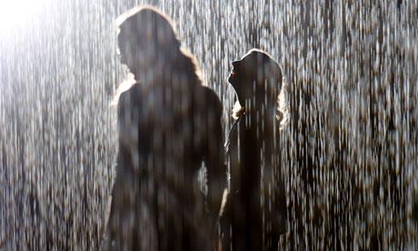 Visitors walk through the Rain Room at the Barbican in London