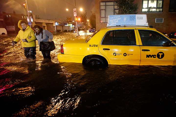 Sandy hits New York: Pedestrians walk past a submerged taxi in Brooklyn