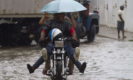 Locals ride a motorbike in a flooded street in Santo Domingo, Haiti