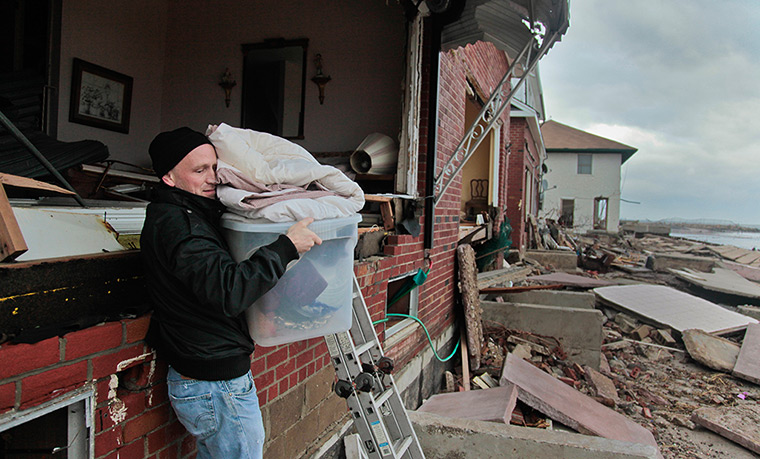 Coastal aftermath: A man removes belongings from his father's beachfront home