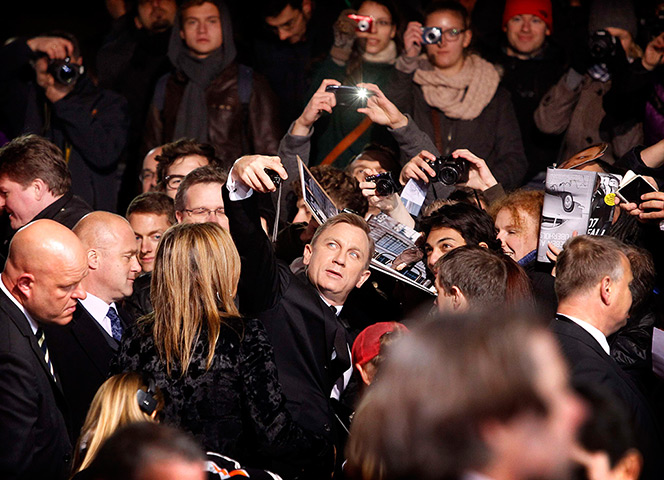 24 hours in pictures: Daniel Craig takes a photograph of himself with fans