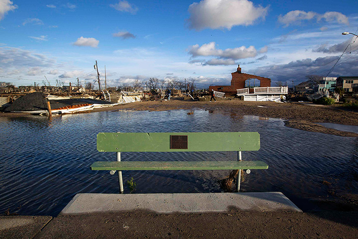 Coastal aftermath update: A bench sits in front of the wreckage of homes in the Breezy Point section