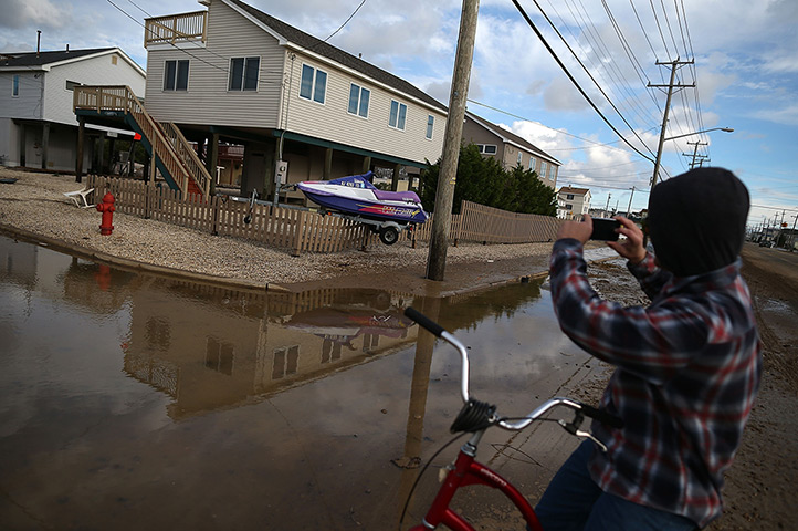 Coastal aftermath update: A boy takes a picture of a jet ski stuck on a fence in Long Beach Island