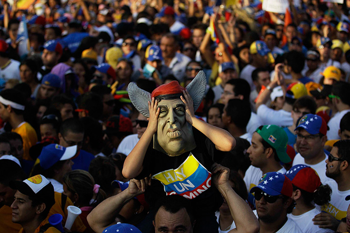 24 hours in pictures: A supporter of Henrique Capriles wears a mask of Venezuelan president Hugo Chavez