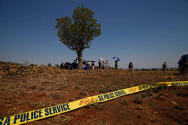 20 Photographs: Striking South African miners wait behind a police cordon