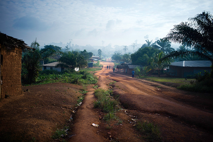 Liberia: People walk through Fishtown in early morning light in River Gee county