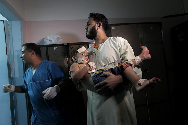 24 hours in pictures: A Palestinian man holds a wounded boy in the Al-Najar hospital 