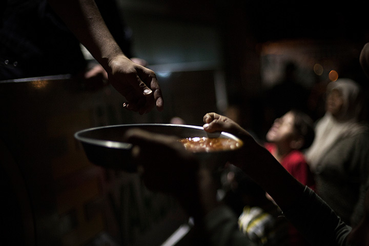 24 hours in pictures: A Syrian boy holds a plate with food to eat at a refugee camp