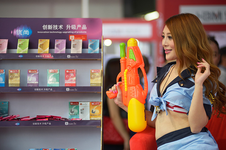 China Sex expo: A model poses with a water pistol on a stand promoting a condom brand