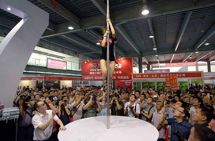China Sex expo: Spectators photograph a pole dancer on the 007 brand condom stand