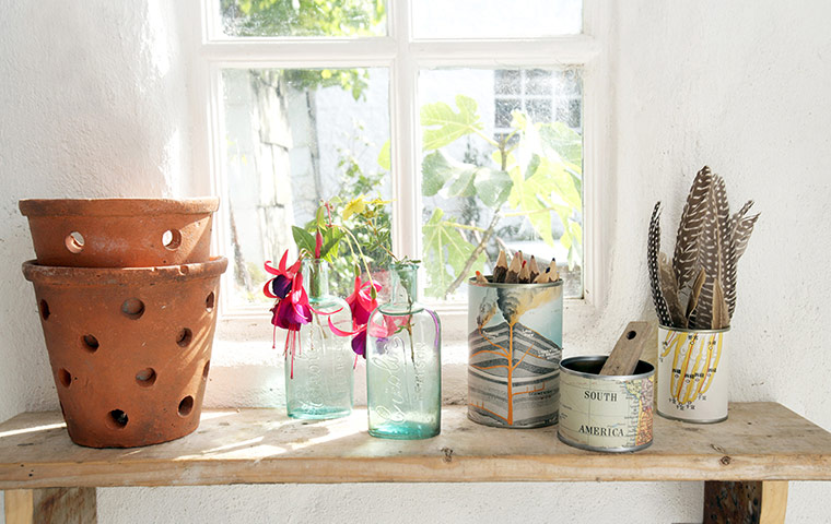 Homes: Recycled: Detail of tins covered in maps on a shelf