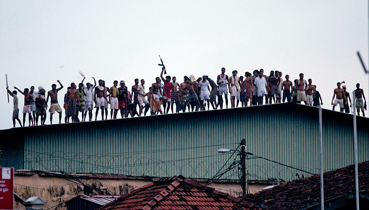 24 hours:  Inmates display guns, on a roof of a prison in Sri Lanka