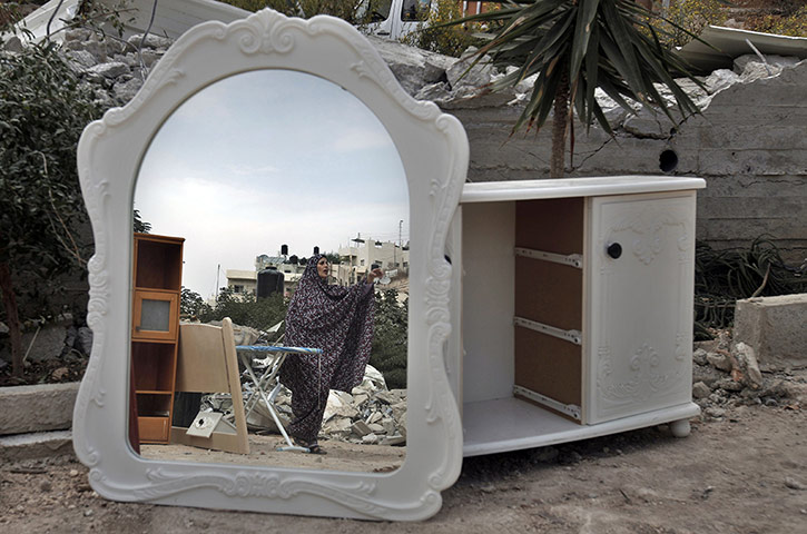 20 Photos: A Palestinian reflected in a mirror from furniture thrown from her home