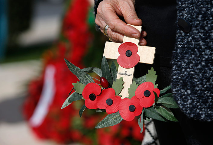 Remembrance Day: Valletta, Malta: A woman carries a remembrance cross and poppies